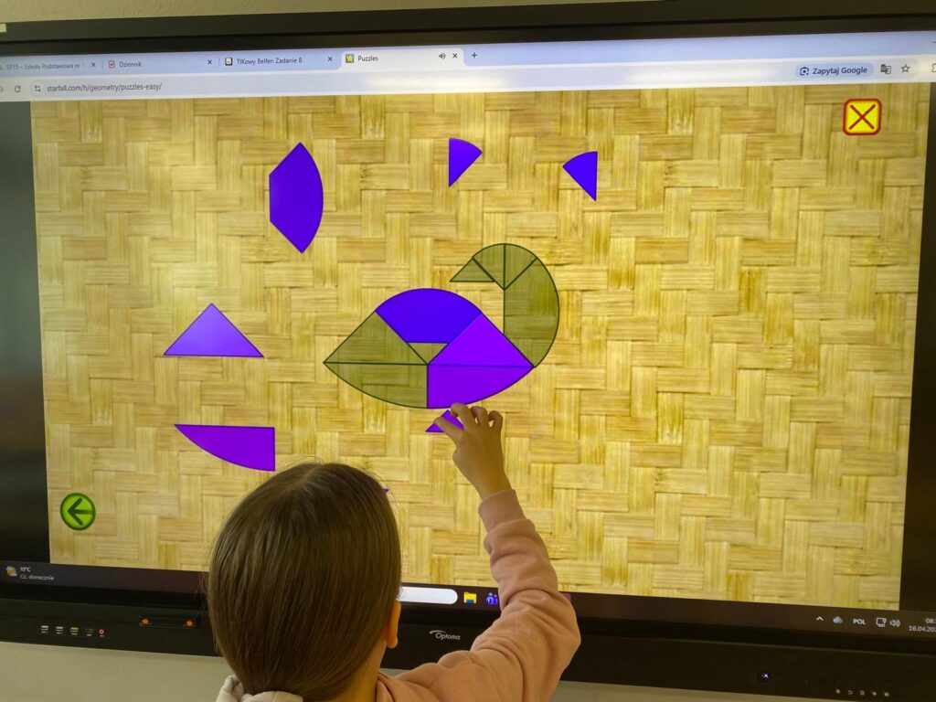 Na zdjęciu uczeń układający tangram na tablicy multimedialnej